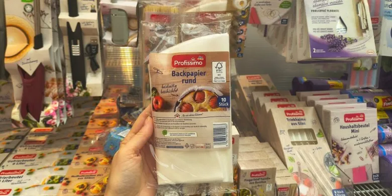 Ruka drží balení kruhového pečicího papíru v obchodě.