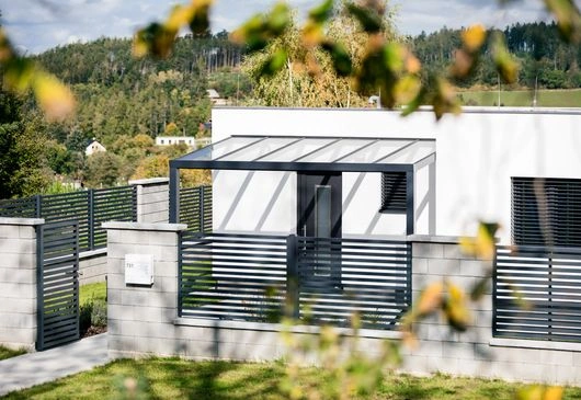Moderní hliníková pergola na fasádě domu s zahradou.