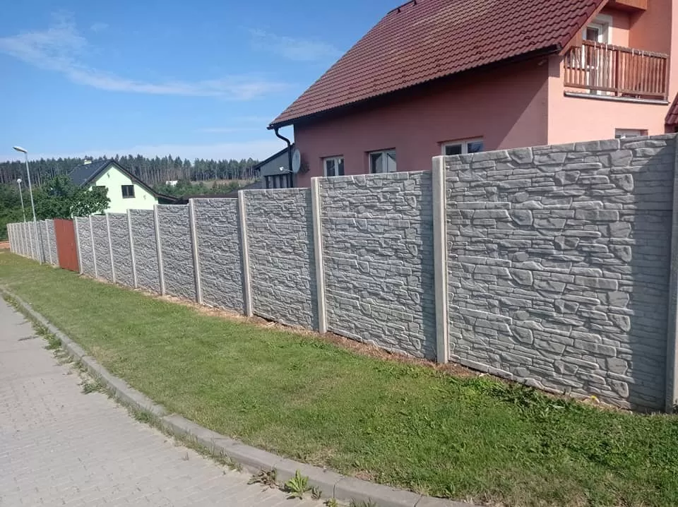 Konkrétní betonový plot s kamennou úpravou u rodinného domu.
