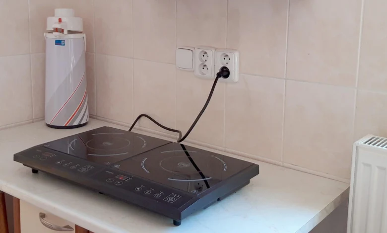 Indukční varná deska zapojená do elektrické zásuvky v kuchyni.