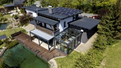 Modern dům s přistavěnou zimní zahradou na pozemku.