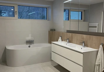 Moderní koupelna po rekonstrukci s vanou a umyvadlem.