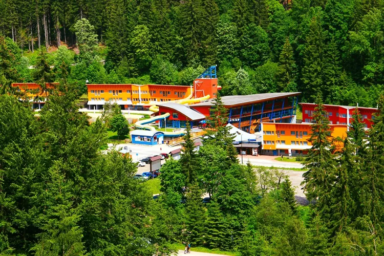 Aquapark ve Špindlerově Mlýně uprostřed lesa s barevnými skluzavkami.