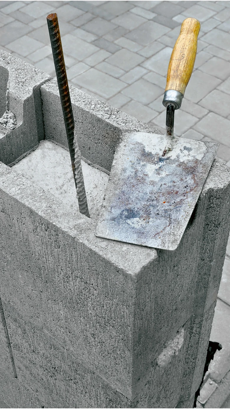 betonový blok s výztuží a kladivem na pozadí dlažby