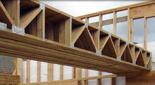 Dřevěná trámová konstrukce stropu s kovovými spojovacími prvky.
