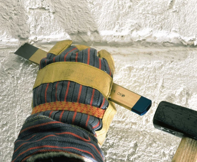 Hand holding chisel and hammer