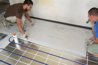 Dva muži montují desky podlahového topení na suchou vrstvu.