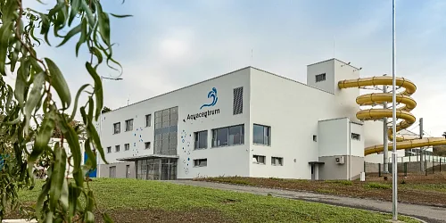 Bílá budova akvaparku s žlutými vodními skluzavkami.