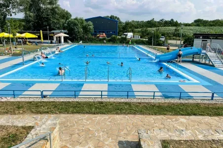 Venkovní bazén v Otrokovicích s vodním skluzavkou a plavci.