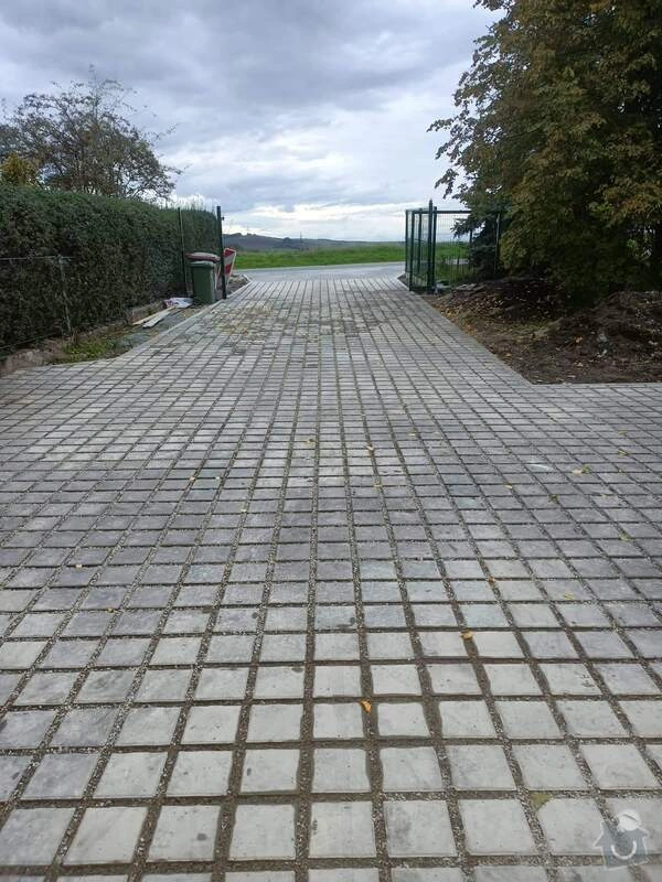 Základní dlažba z kostky na svažitém terénu vedoucí k bráně.