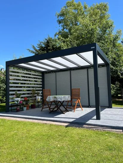 Moderní pergola s roletami a venkovním jídelním stolem na zahradě.