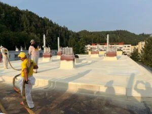 Pracovníci nanášejí PUR pěnovou izolaci na střechu.