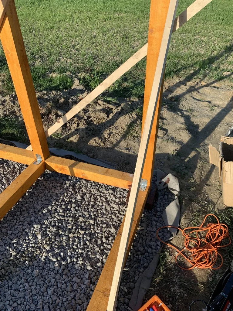 Částečně postavený dřevěný rám pro zahradní budovu na štěrku.