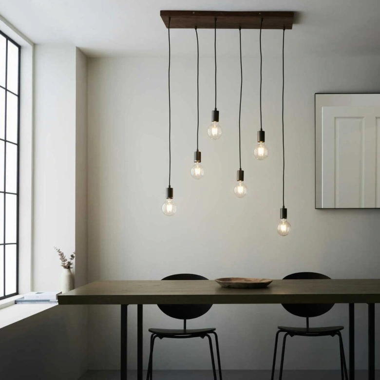 Modern jídelna s černými židlemi a lampami v minimalistickém interiéru.