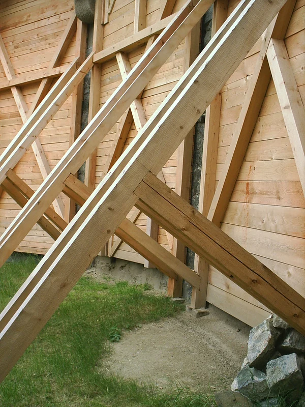 Dřevěná konstrukce s tesanými spoji v rámu budovy.