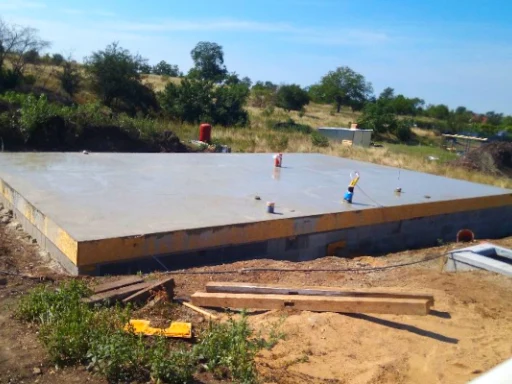Čerstvě nalitý samonivelační betonový základ na staveništi.
